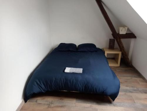 Bett mit blauer Decke in einem Zimmer in der Unterkunft Gîte familiale au cœur du village in Villiers-au-Bouin
