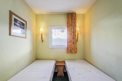 deux lits dans une chambre avec une fenêtre dans l'établissement Résidence Les Horizons d'Huez - maeva Home - Appartement 2 pièces 4 personnes Sélection MAE-3559, à Huez