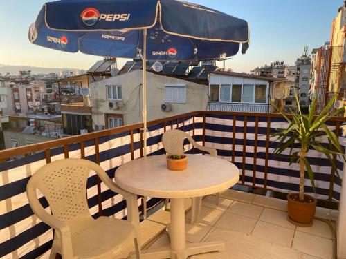 einen Tisch und Stühle auf einem Balkon mit Sonnenschirm in der Unterkunft City Center in Antalya