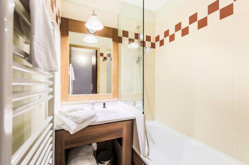 La salle de bains est pourvue d'un lavabo, d'une baignoire et d'un miroir. dans l'établissement Résidence Les Temples du Soleil - maeva Home - Appartement 2 pièces 5 perso 29, à Val Thorens