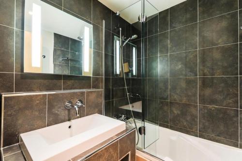 bagno con lavandino, vasca e specchio di Résidence Les Chalets du Forum - maeva Home - Appartement 2 pièces 6 person 30 a Courchevel