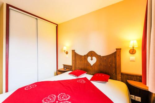 - une chambre avec un lit rouge et 2 oreillers rouges dans l'établissement Résidence L'Alpaga - maeva Home - Appartement 2 pièces 5 personnes Confort MAE-1867, à La Salle Les Alpes