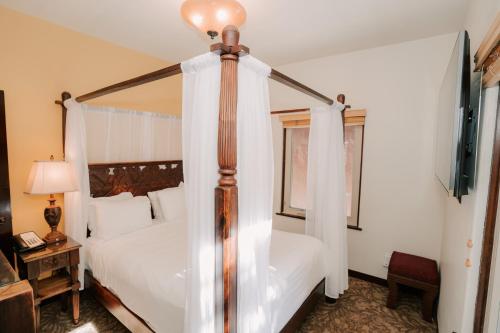 a bedroom with a four poster bed with curtains at Pantai Inn in San Diego
