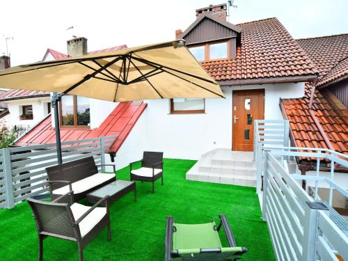 a patio with chairs and an umbrella on the grass at Holiday home 200 qm Kolobrzeg in Kołobrzeg