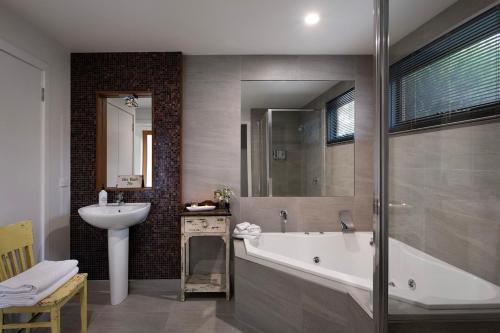 a bathroom with a sink and a bath tub and a sink at Alofi- stunning views and a private cinema room! in Hepburn Springs