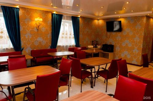 a restaurant with wooden tables and red chairs at Hotel Antalya in Zaozërnyy