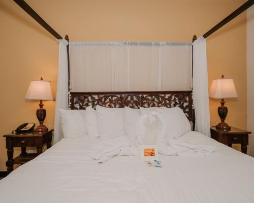 a large white bed with two lamps and a sign on it at Pantai Inn in San Diego