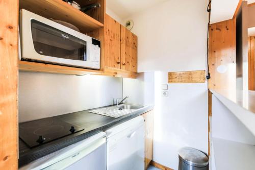 une petite cuisine avec un évier et un micro-ondes dans l'établissement Résidence Les Brigues - maeva Home - Appartement 2 pièces 6 personnes Confort MAE-7008, à Courchevel