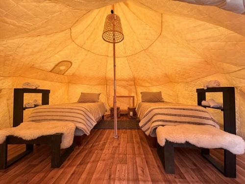 Una habitación con 2 camas en una tienda en Chilenativo Riverside Camp en Torres del Paine