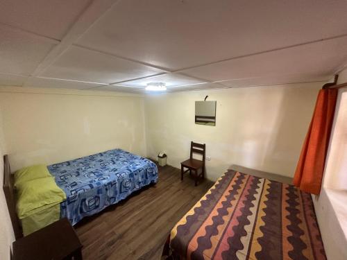 um quarto com duas camas e uma cadeira. em Aventura Chachapoyas Backpackers em Chachapoyas