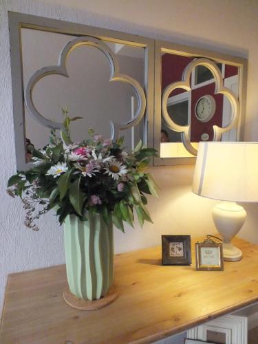 a vase of flowers on a table next to a lamp at Bed&Breakfast Wagner "im Alten Pfarrhaus" in Neuruppin