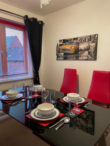 a dining room table with red chairs and a table with glasses at Holcott's Coach-House in Lincoln