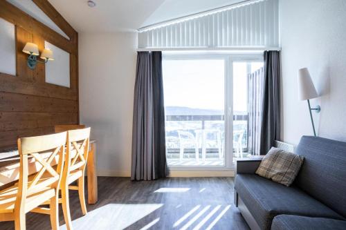 un salon avec un canapé, une table et une fenêtre dans l'établissement Résidence Le Pédrou - maeva Home - Studio 4 personnes Sélection - vue exceptionnelle MAE-7351, à Font-Romeu-Odeillo-Via