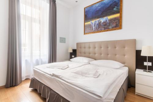 um quarto com uma cama grande e lençóis brancos em Riverside Palace Suites em Praga