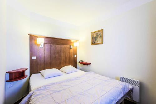 1 dormitorio con cama blanca y cabecero de madera en Résidence Le Mont Soleil - maeva Home - Appartement 2 Pièces 5 Personnes - 38 en Mâcot La Plagne