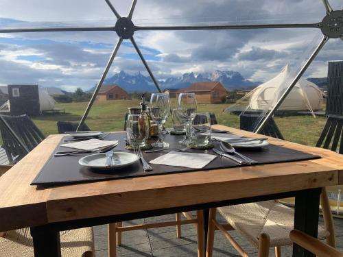 a wooden table with glasses and plates on it at Chilenativo Riverside Camp in Torres del Paine