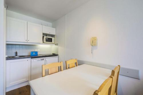 une petite cuisine avec une table et des chaises blanches dans l'établissement Résidence Le Thabor - maeva Home - Appartement 2 Pièces 5 Personnes - Confort MAE-0345, à Le Désert