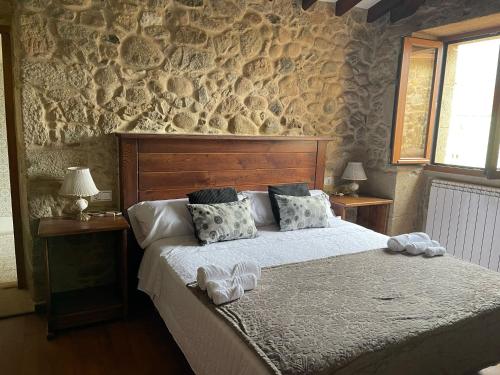 een slaapkamer met een groot bed en een stenen muur bij Campomuiños in Pobra do Caramiñal