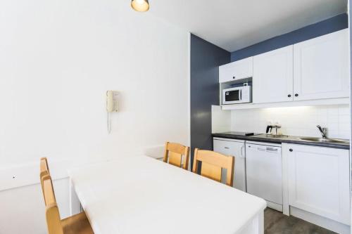 une cuisine avec des armoires blanches et une table et des chaises dans l'établissement Résidence Le Thabor - maeva Home - Appartement 2 pièces 5 personnes Confort MAE-2491, à Le Désert