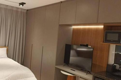 a hotel room with a bed and a flat screen tv at Flat novinho na Bela Vista in São Paulo