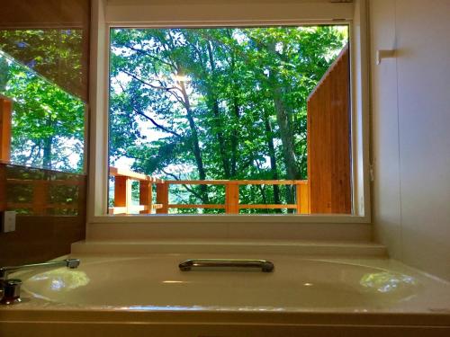 Rental Villa Karuizawa Honors Hill - Vacation STAY 04109v في Oiwake: حوض الحمام مع نافذة مطلة على شجرة