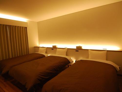 Rental Villa Karuizawa Honors Hill - Vacation STAY 04109v في Oiwake: سريرين في غرفة مع أضواء على الحائط