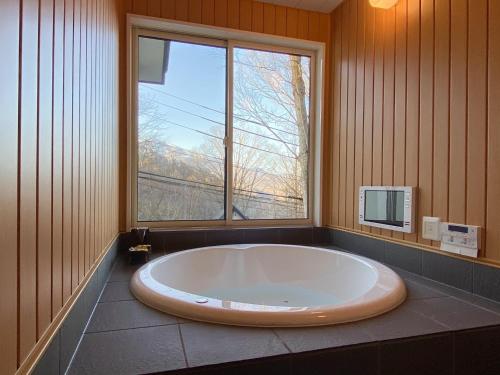 baño con bañera grande y ventana en Rental Villa Karuizawa Honors Hill - Vacation STAY 02160v en Oiwake