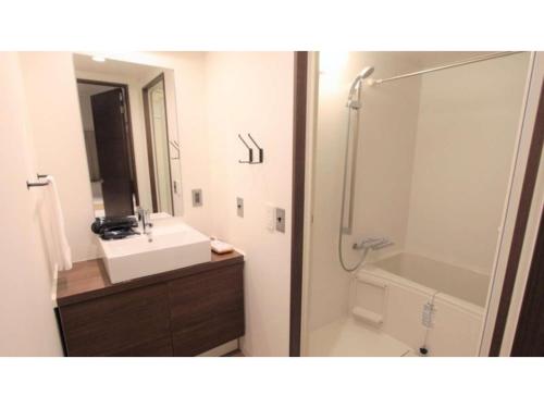 La salle de bains est pourvue d'un lavabo, d'une douche et d'un miroir. dans l'établissement River Side Arashiyama - Vacation STAY 86277v, à Kyoto