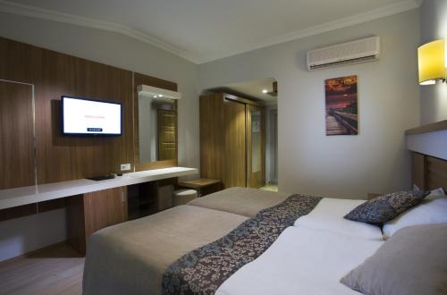 a hotel room with a bed and a desk with a television at Sun Club Side Hotel - All inclusive in Side