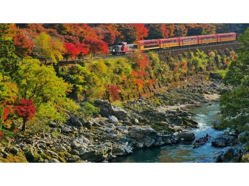 a train on a bridge over a river with trees at River Side Arashiyama - Vacation STAY 86224v in Kyoto
