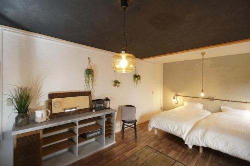 a bedroom with two beds and a desk with a tv at Guesthouse Yumi to Ito - Vacation STAY 94562v in Nagano