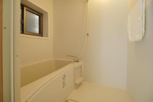 Guesthouse Yumi to Ito - Vacation STAY 94562v في ناغانو: حمام أبيض مع حوض استحمام ونافذة