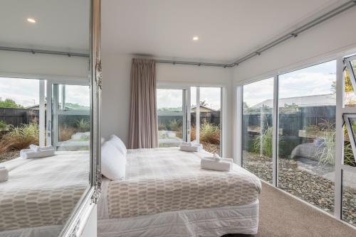 a bedroom with a bed and large glass windows at Lakeside Gem in Rotorua