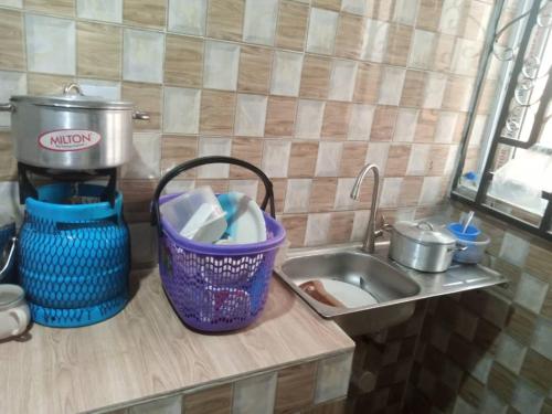 a kitchen counter with a sink and a basket of dishes at Tradebybata Homes, Abeokuta around FUNAAB in Abeokuta