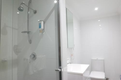 a bathroom with a shower and a toilet and a sink at Parkville Place Serviced Apartments in Melbourne