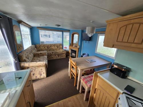 an rv kitchen and living room with a table and a couch at The daxie 3-Bed caravan in Butlins Skegness in Skegness