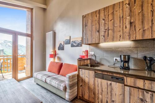 une cuisine avec des armoires en bois et un canapé dans une pièce dans l'établissement Résidence Arietis - Atria-Crozats - maeva Home - Appartement 2 Pièces 5 Personnes - Prestige MAE-8129, à Morzine