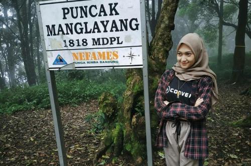 una mujer de pie junto a un cartel en el bosque en Bino kasih, en Balong