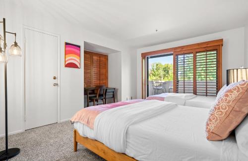 ein weißes Schlafzimmer mit einem Bett und einem Tisch in der Unterkunft Sweet Citrus Condo - A Ryson Property in Palm Springs
