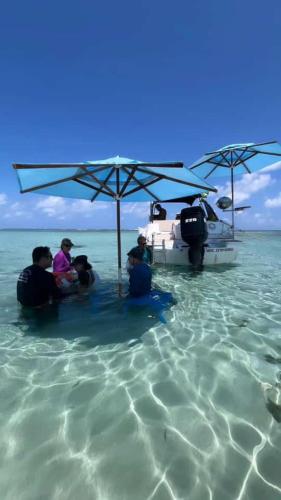 a group of people sitting under an umbrella in the water at Pousada Dona Felicidade Carneiros in Tamandaré