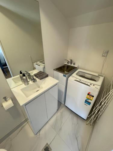 uma pequena cozinha com um lavatório e um fogão em Modern Home by the Reserve em Auckland