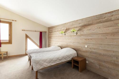 een slaapkamer met 2 bedden en een houten muur bij Résidence Le Christiana - maeva Home - Appartement 3 Pièces 7 Personnes - S 70 in Saint-Bon-Tarentaise