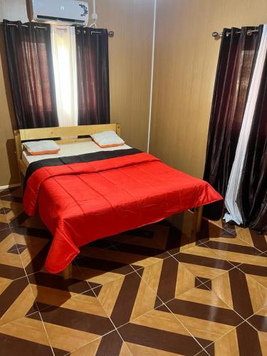 Una cama con una manta roja encima de una habitación en Residencial Pensão Bom Desconto, en Principe