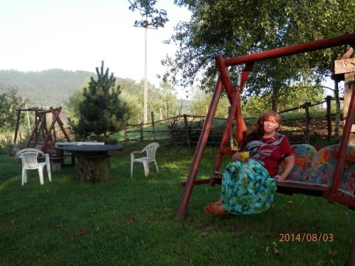 a woman sitting on a swing in a yard at Zagroda Agroturystyczna Wiecha in Mieroszów