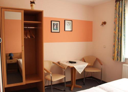 Cette chambre comprend une table, des chaises et un lit. dans l'établissement Gästehaus Zum Felsenkeller, à Nordhausen