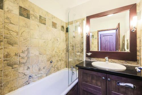 ein Badezimmer mit einer Badewanne, einem Waschbecken und einem Spiegel in der Unterkunft Résidence Les Arcs Le Village - maeva Home - Pièces Prestige 60 in Bourg-Saint-Maurice