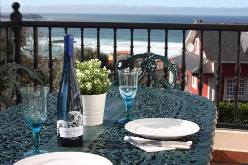 - une table avec une bouteille de vin et des verres sur un balcon dans l'établissement Siete Playas Surf House, à Valdoviño