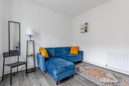 a living room with a blue couch and yellow pillows at Spacious & Newly Renovated 4BD House East Ham! in London