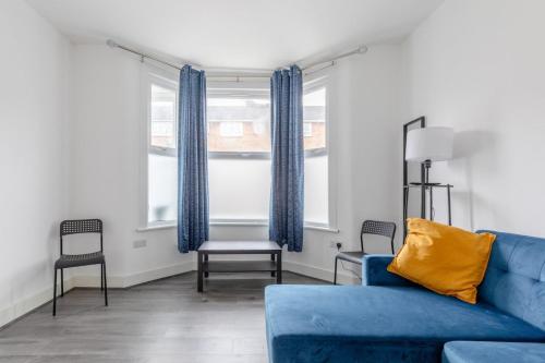 a living room with a blue couch and two windows at Spacious & Newly Renovated 4BD House East Ham! in London