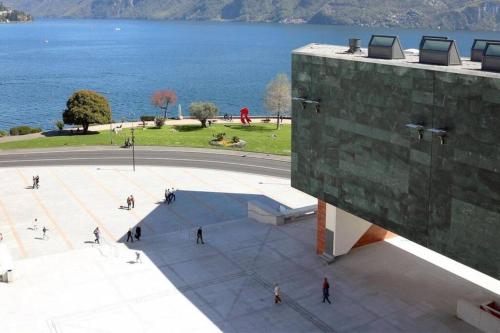 a group of people walking around a building next to the water at Lugano Gem Mini Suite Moderna in Lugano